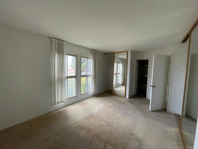 unfurnished bedroom featuring light colored carpet and two closets