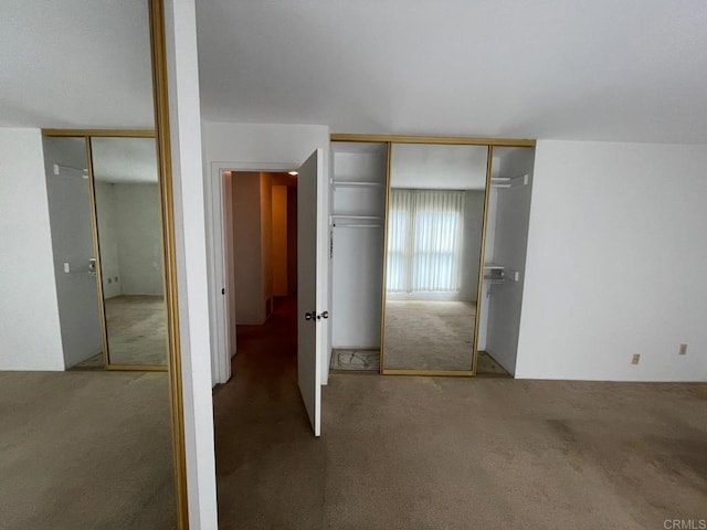 unfurnished bedroom featuring carpet and two closets