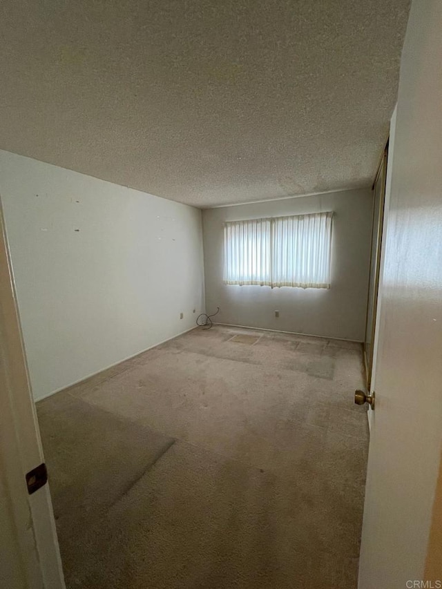 empty room featuring light carpet and a textured ceiling