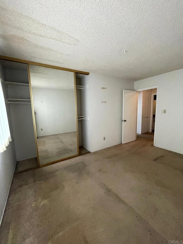 unfurnished bedroom with carpet floors, a textured ceiling, and a closet