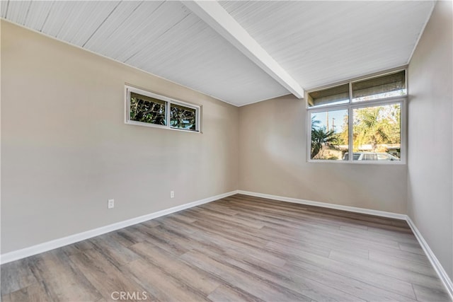 spare room with beamed ceiling and light wood-type flooring