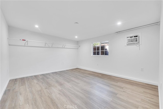 unfurnished room with a wall unit AC and light hardwood / wood-style floors