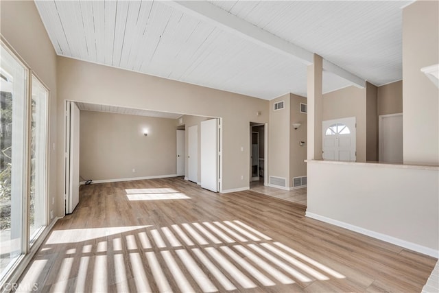 spare room featuring beamed ceiling and light hardwood / wood-style floors