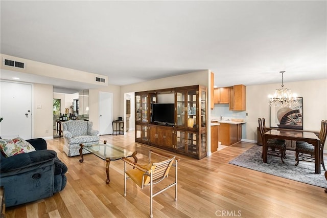 living room featuring an inviting chandelier and light hardwood / wood-style flooring