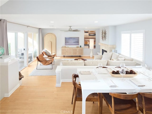 dining space with ceiling fan, a premium fireplace, and light hardwood / wood-style flooring