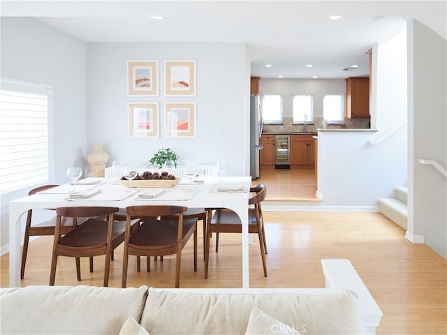 dining area featuring wine cooler and light hardwood / wood-style flooring