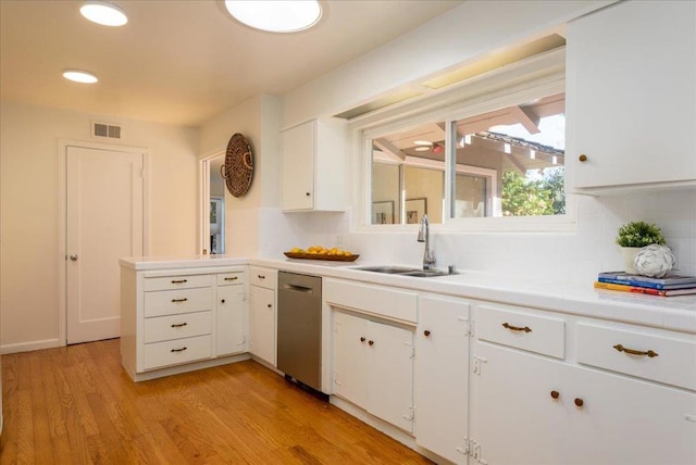 kitchen featuring dishwasher, sink, white cabinets, backsplash, and light hardwood / wood-style flooring