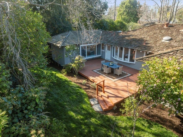 rear view of property with a wooden deck and a lawn