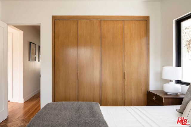 bedroom featuring a closet and light parquet flooring