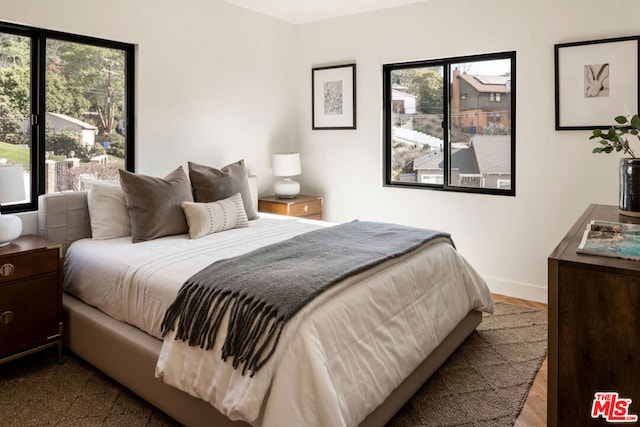 bedroom with multiple windows and light hardwood / wood-style flooring