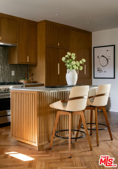 kitchen with tasteful backsplash, a breakfast bar area, light parquet flooring, and high end stainless steel range oven