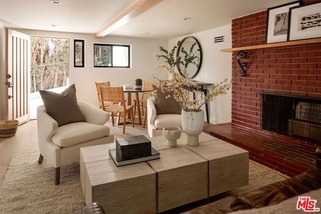 living room featuring beamed ceiling and a brick fireplace