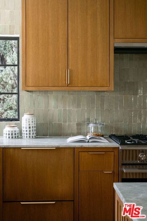 kitchen with stainless steel gas stove and decorative backsplash