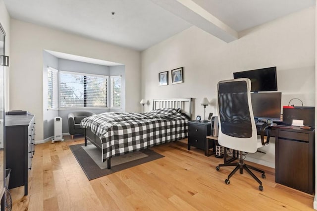 bedroom featuring beamed ceiling and light wood-type flooring