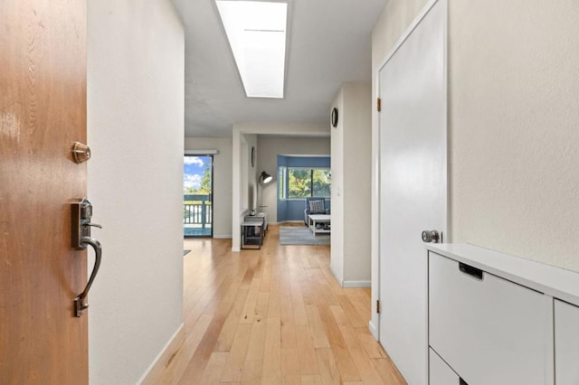 hall with light hardwood / wood-style flooring and a skylight