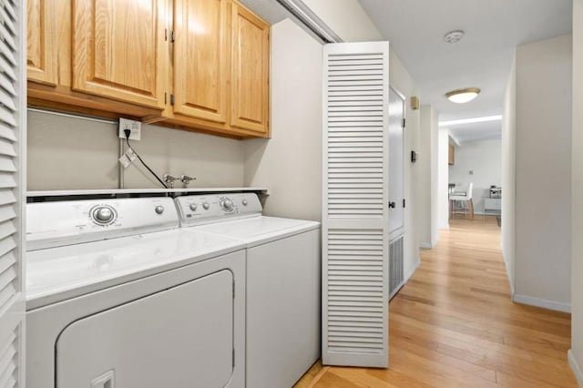 laundry room with washer and dryer, cabinets, and light wood-type flooring