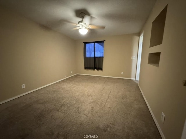 empty room featuring ceiling fan and dark colored carpet