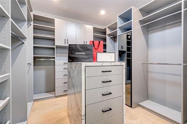 walk in closet with light hardwood / wood-style floors