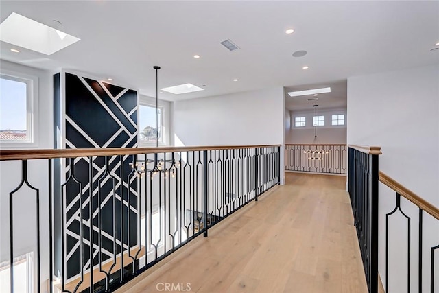 hall with a healthy amount of sunlight, a chandelier, and hardwood / wood-style floors