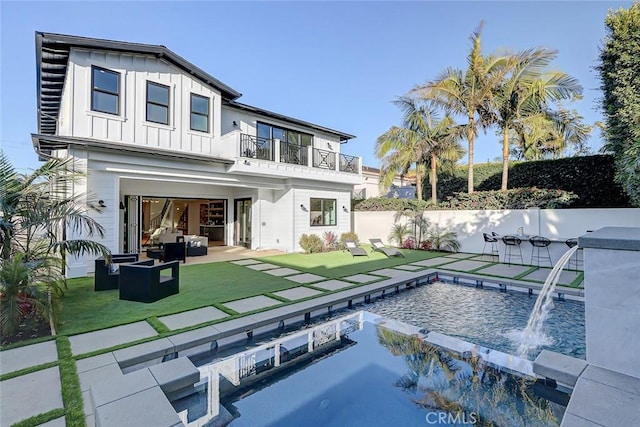 back of house featuring pool water feature, a balcony, a lawn, an outdoor hangout area, and a fenced in pool