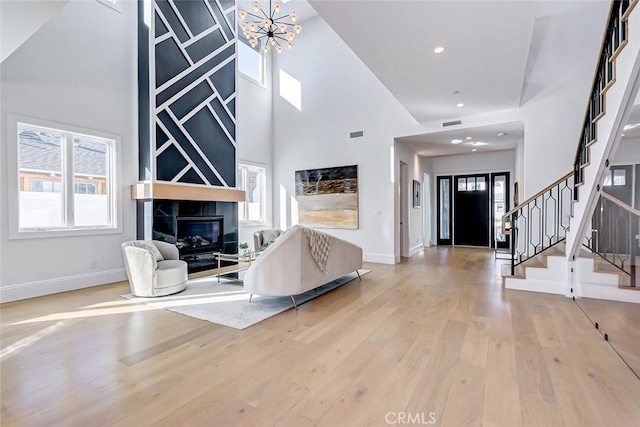 entrance foyer featuring a towering ceiling, a tiled fireplace, hardwood / wood-style floors, and a notable chandelier