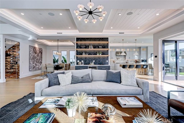 living room featuring an inviting chandelier, a tray ceiling, and a wealth of natural light