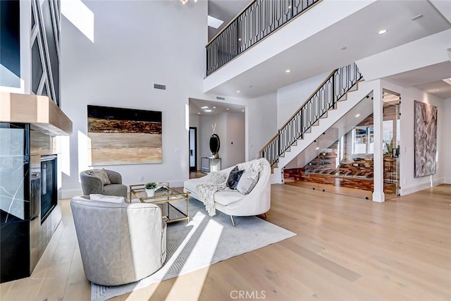 living room with a towering ceiling and light hardwood / wood-style floors