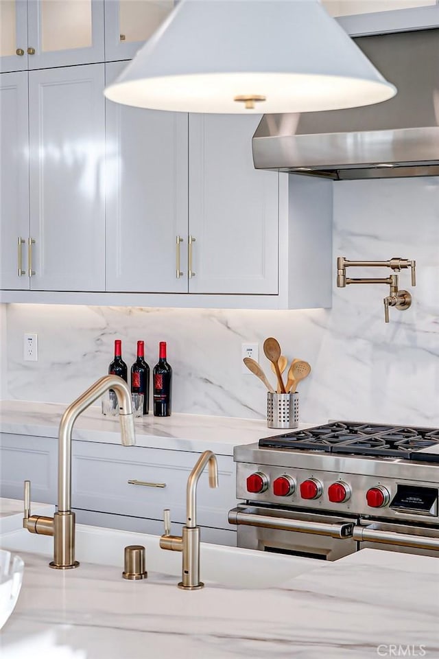 kitchen featuring double oven range, ventilation hood, and backsplash