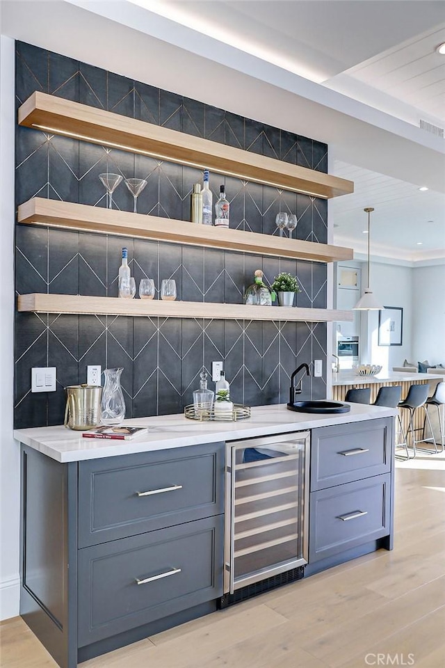 bar featuring gray cabinets, decorative light fixtures, wine cooler, decorative backsplash, and light hardwood / wood-style floors