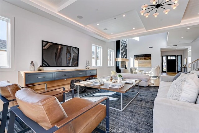 living room featuring plenty of natural light, a chandelier, and a raised ceiling