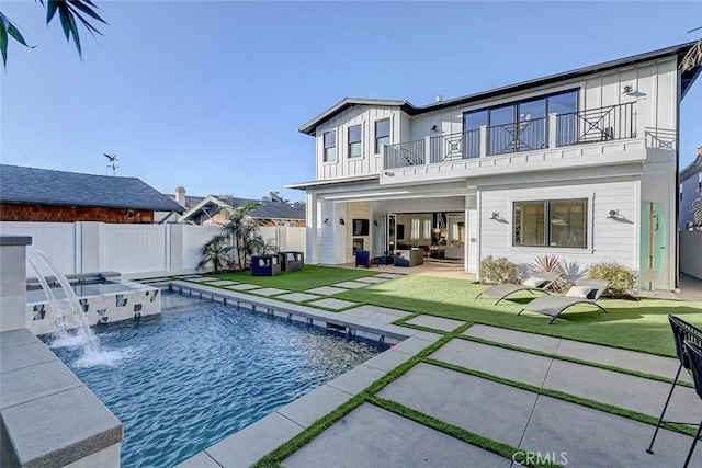 back of house featuring pool water feature, a patio area, a balcony, a yard, and a swimming pool with hot tub