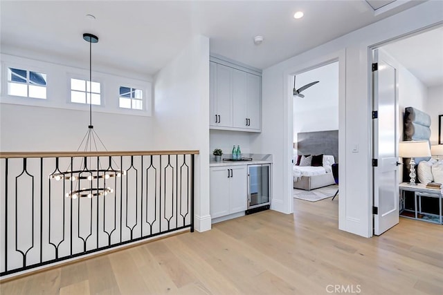 hall featuring beverage cooler, light hardwood / wood-style flooring, and a notable chandelier