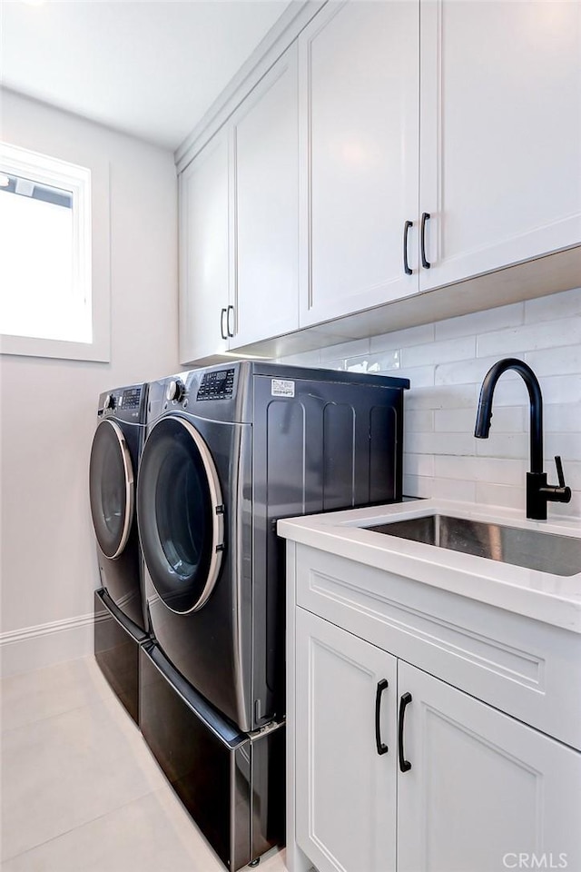 washroom featuring separate washer and dryer, sink, light tile patterned floors, and cabinets