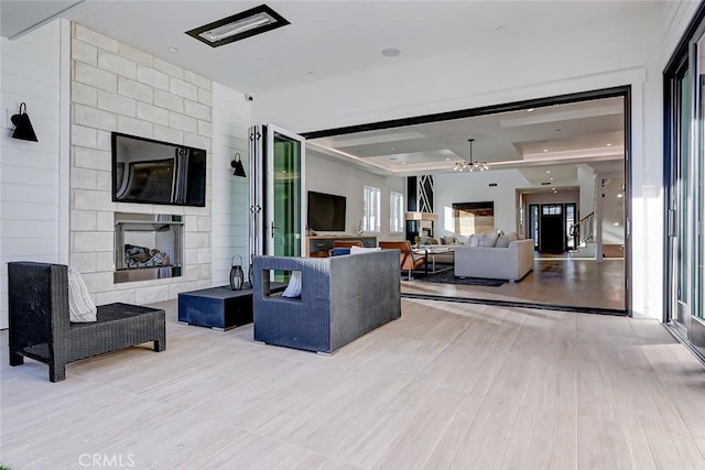 living room with a tray ceiling, a large fireplace, and light wood-type flooring