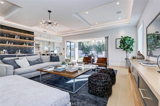 living room featuring wood ceiling, a raised ceiling, light hardwood / wood-style floors, and a notable chandelier