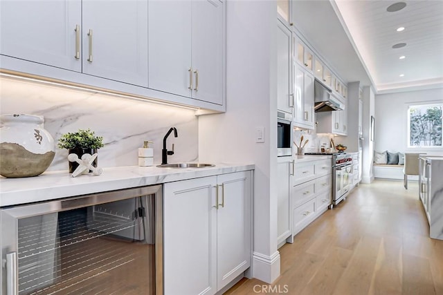 kitchen featuring sink, stainless steel stove, beverage cooler, decorative backsplash, and white cabinets