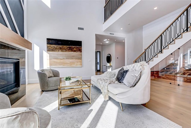 living room featuring a high ceiling, a fireplace, and light hardwood / wood-style flooring