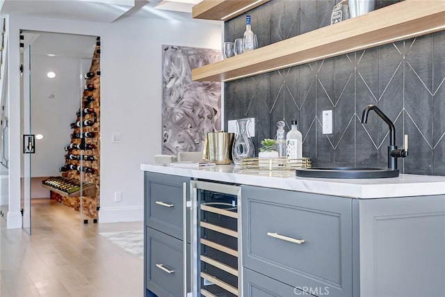 bar featuring sink, beverage cooler, and decorative backsplash