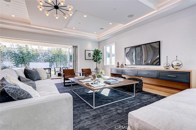 living room featuring a raised ceiling, dark hardwood / wood-style floors, and an inviting chandelier