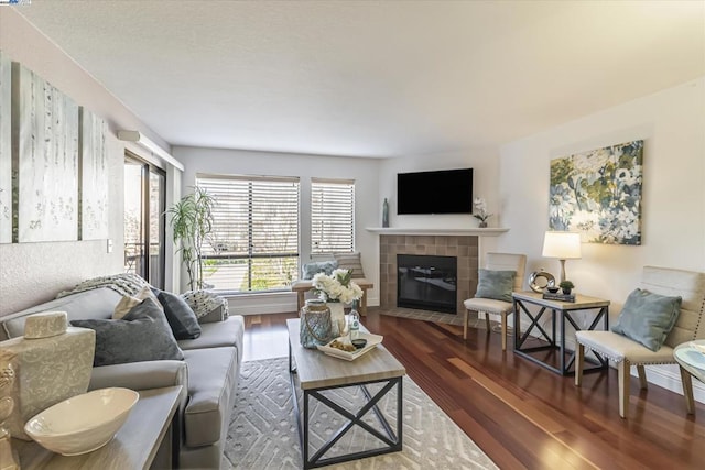 living room with a tiled fireplace and dark hardwood / wood-style floors