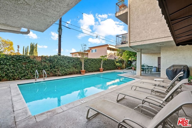 view of swimming pool featuring area for grilling and a patio area