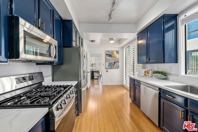 kitchen with blue cabinets, appliances with stainless steel finishes, sink, and light hardwood / wood-style floors