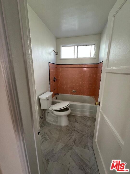 bathroom with tiled shower / bath and toilet