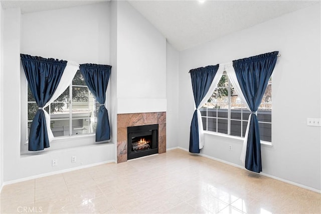 unfurnished living room with a tiled fireplace, vaulted ceiling, and tile patterned floors