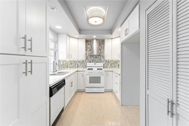 kitchen featuring sink, wall chimney range hood, white cabinets, and white appliances