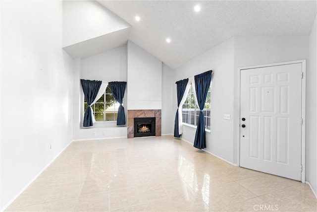 unfurnished living room with a tiled fireplace, high vaulted ceiling, and a textured ceiling