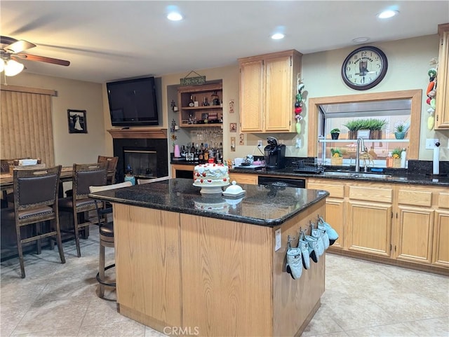 kitchen with a kitchen island, sink, dark stone countertops, and light brown cabinetry