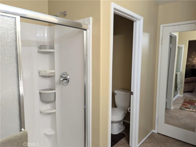 bathroom featuring tile patterned floors, toilet, and a shower with door