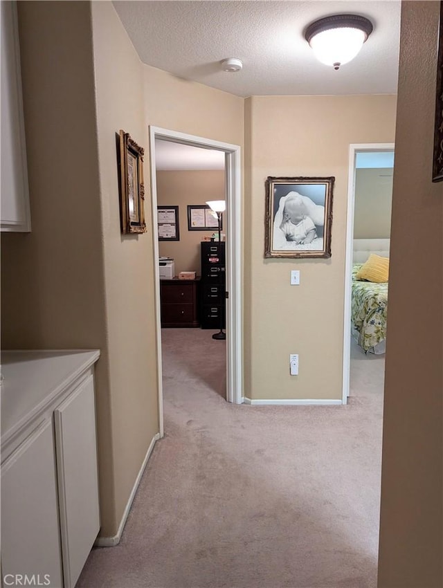 hallway featuring light carpet and a textured ceiling