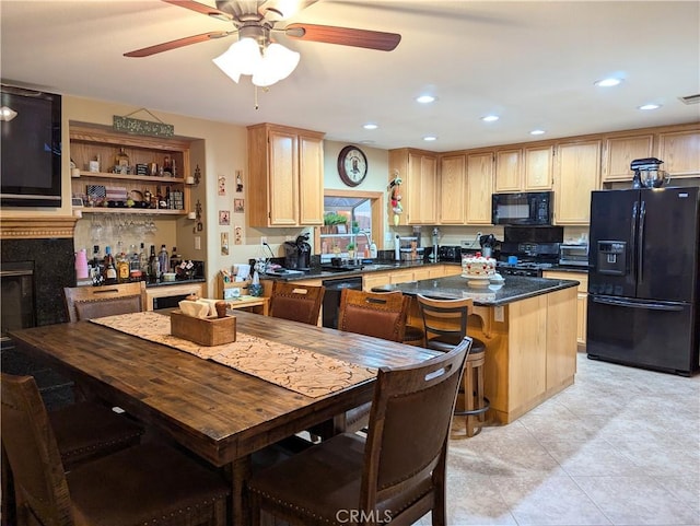 kitchen featuring a breakfast bar, ceiling fan, black appliances, a kitchen island, and light brown cabinets